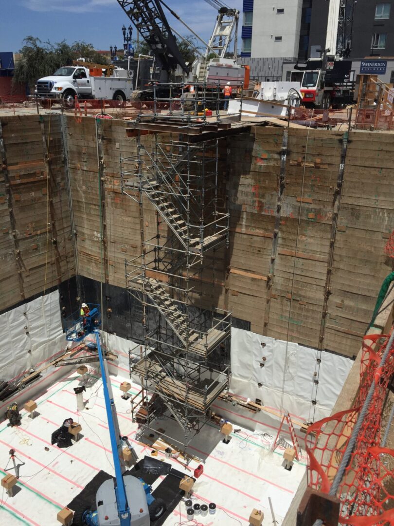 Deep excavation site with scaffolding and construction materials inside.